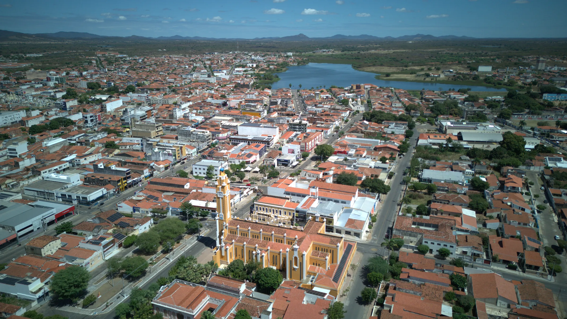 Vista aérea de Cajazeiras: a catedral amarela em primeiro plano, o centro da cidade e o Açude Grande ao fundo, com as serras no horizonte